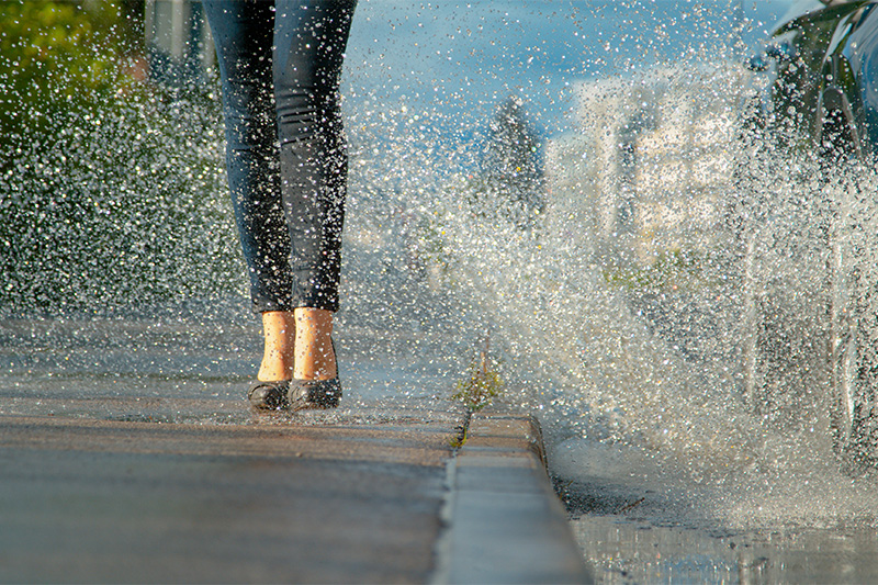 Woman splashed by car with wet shoes