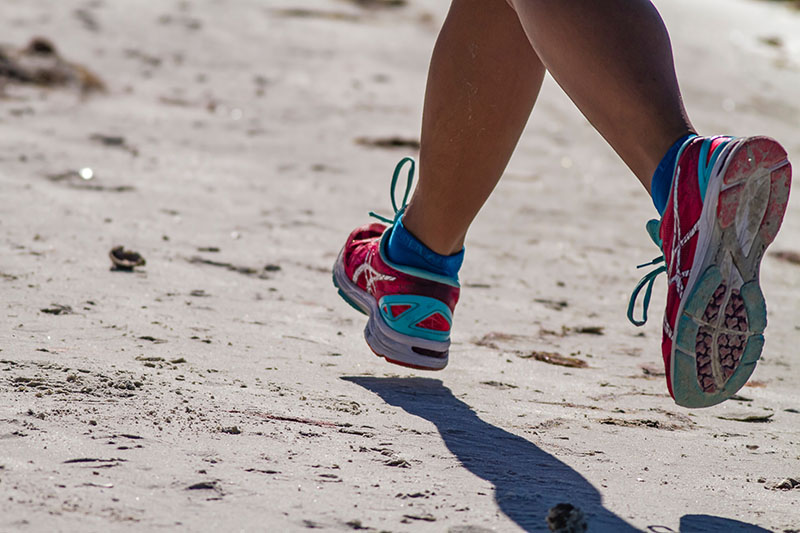 Person in running shoes running on sand