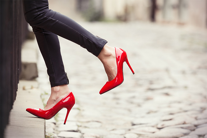 Woman wearing skinny bright red shoes on a cobbled street