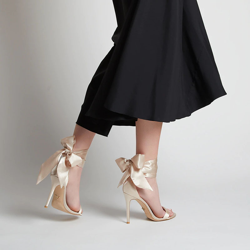 Woman wearing Veerah Venus Strappy Heels with ribbon accessory and a long black dress