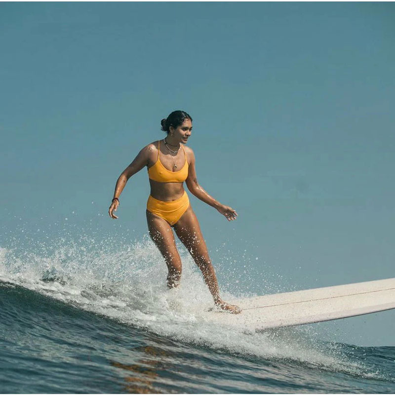Surfer surfing while wearing orange Do Good Swimwear Jazzy High Waist Bottoms